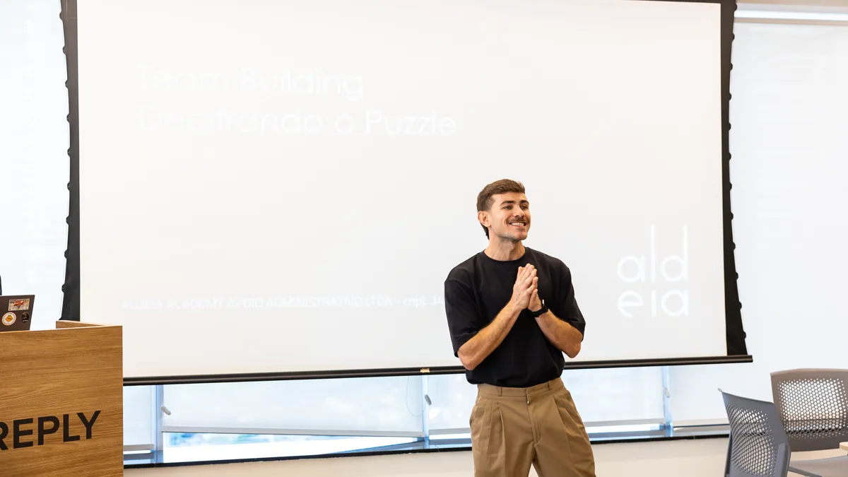 Facilitador conduzindo uma atividade de team building diante de uma tela de apresentação